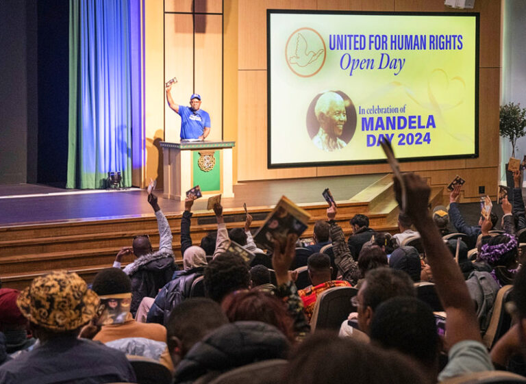 audience and human rights volunteer at podium in community centre