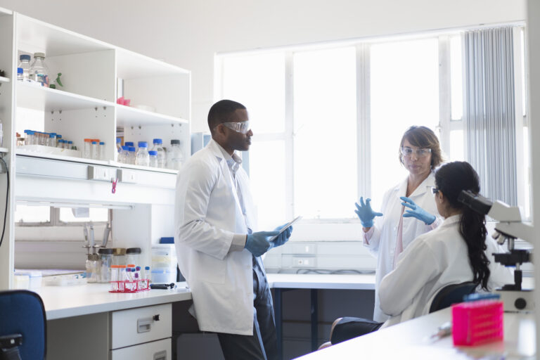 three scientists chat at a lab bay