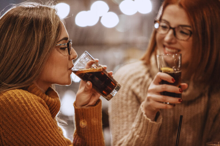 two similar looking people consuming soft drinks