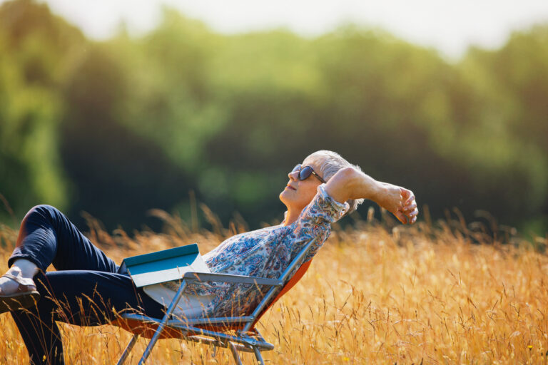 relaxed person with book on lap sitting in field