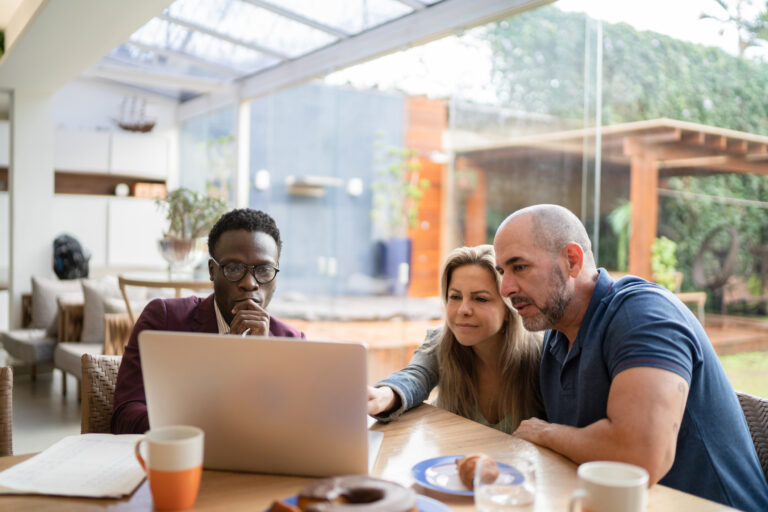 three investors gather around laptop