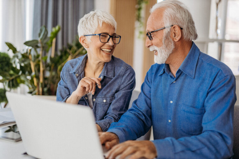 senior couple at laptop smiling gettyimages 1323096524